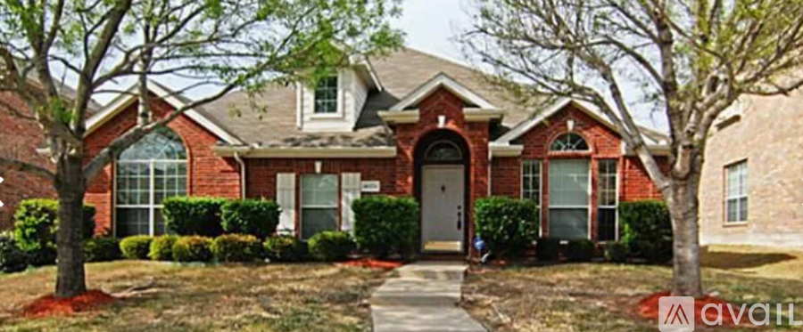 A red brick house with a white trim and a grey door.