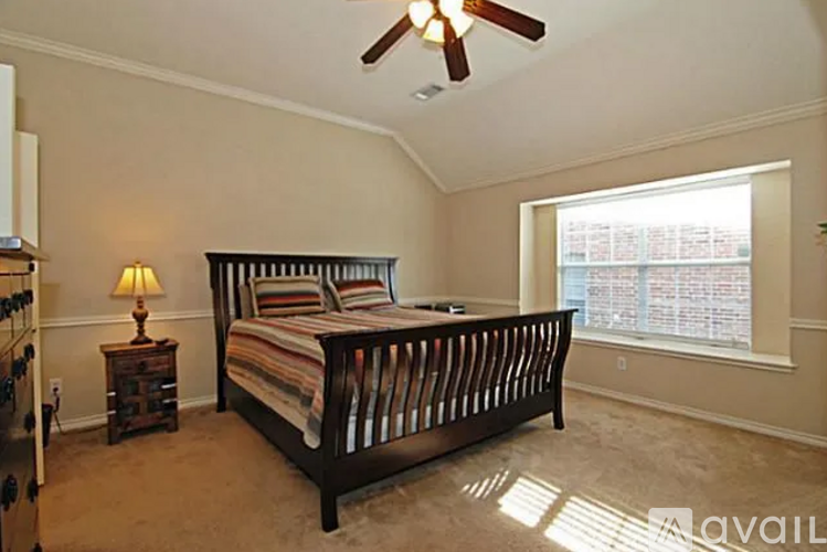 A bedroom with a large bed and a ceiling fan.