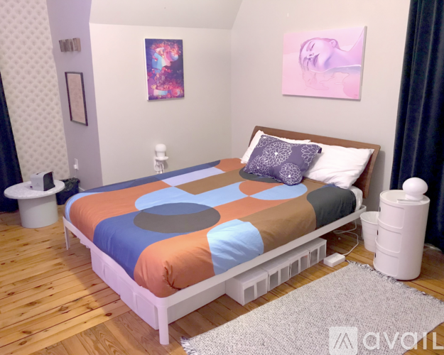 A bedroom with a bed, nightstand, and a painting on the wall.