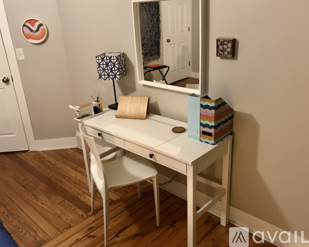 A white desk with a chair and a mirror in a room.
