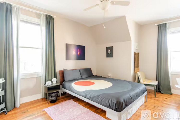 A bedroom with a bed, a ceiling fan, and a window with curtains.