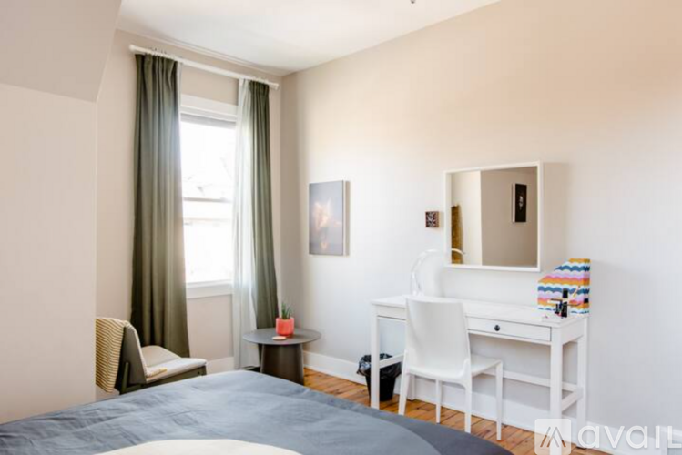 A bedroom with a bed, desk, chair, and window.