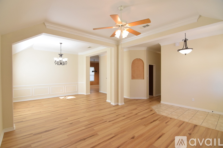 A spacious room with wooden floors and a ceiling fan.