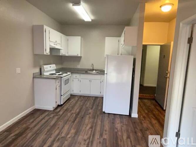A kitchen with white appliances and wooden floors.