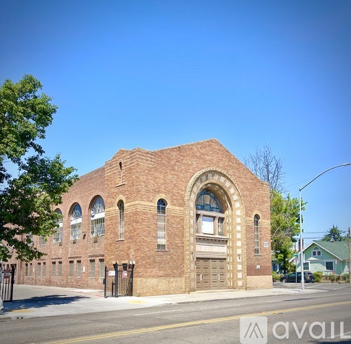 A large red brick building with arched windows and a closed gate.
