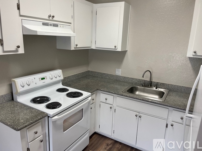 A kitchen with white cabinets and a stove top oven.