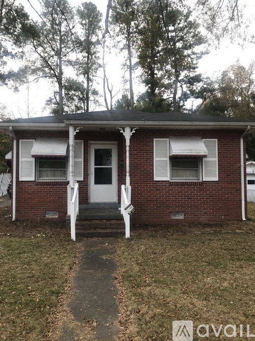 A small red brick house with a white door and a porch.