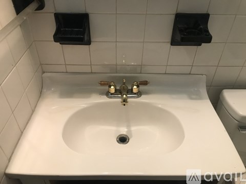 A white sink with a gold faucet in a bathroom.