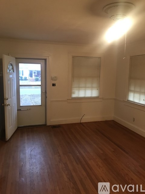 A room with wooden floors and a window with blinds.