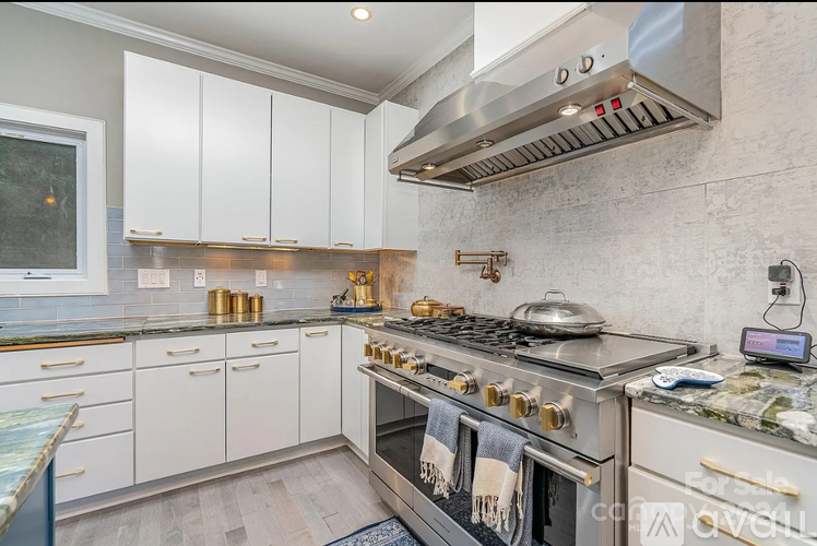 A modern kitchen with a stove top oven and white cabinets.