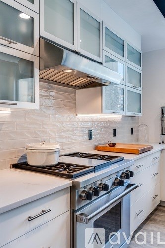 A modern kitchen with a stove top oven and white cabinets.