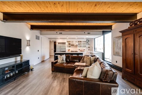 A modern living room with a brown leather couch and wooden floors.