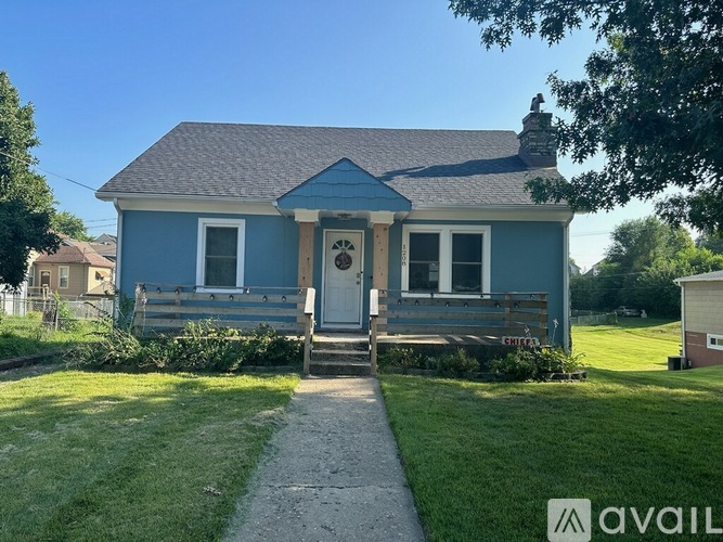 A blue house with a porch and a sign that says "AVAIL".