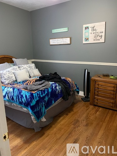 A bedroom with a bed, dresser, and two framed pictures on the wall.