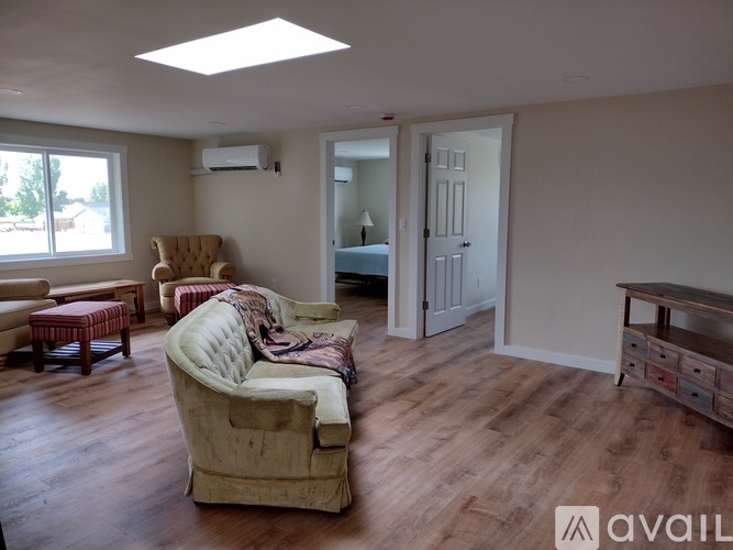 A living room with a couch, chair, ottoman, and a window.