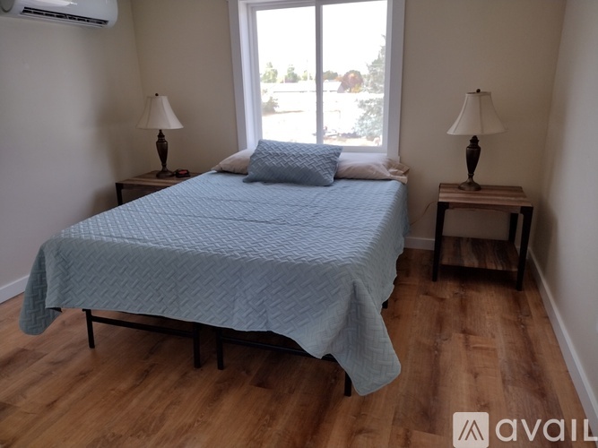 A bedroom with a bed, two lamps, and a window.