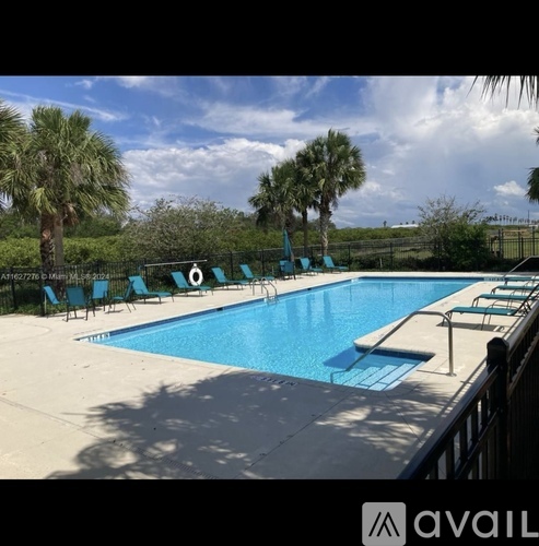 A pool surrounded by trees and chairs.