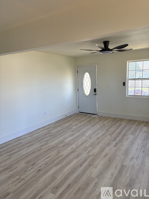 A room with a ceiling fan and wooden flooring.