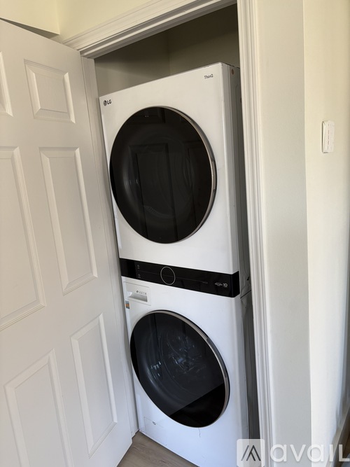 A white washing machine is installed in a small space next to a white door.