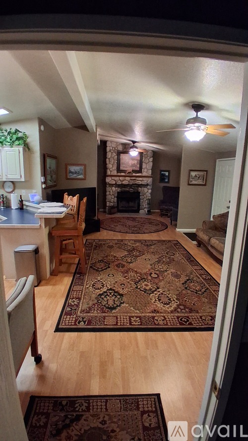 A living room with a rug on the floor and a fireplace in the background.