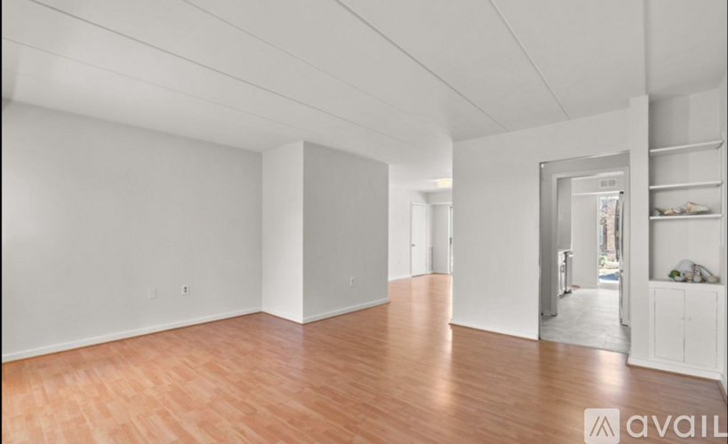 A spacious room with wooden flooring and white walls.