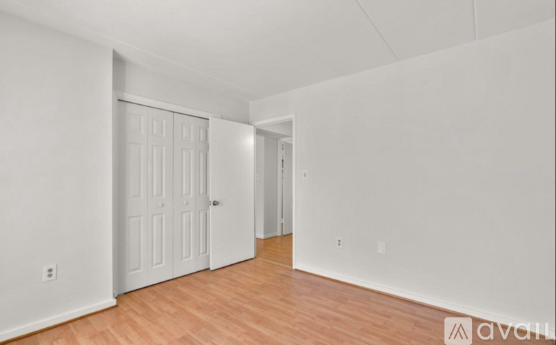A room with a white door and wooden flooring.