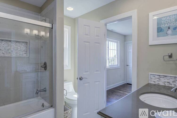 A bathroom with a glass shower stall, a white toilet, a white door, and a sink with a marble countertop.