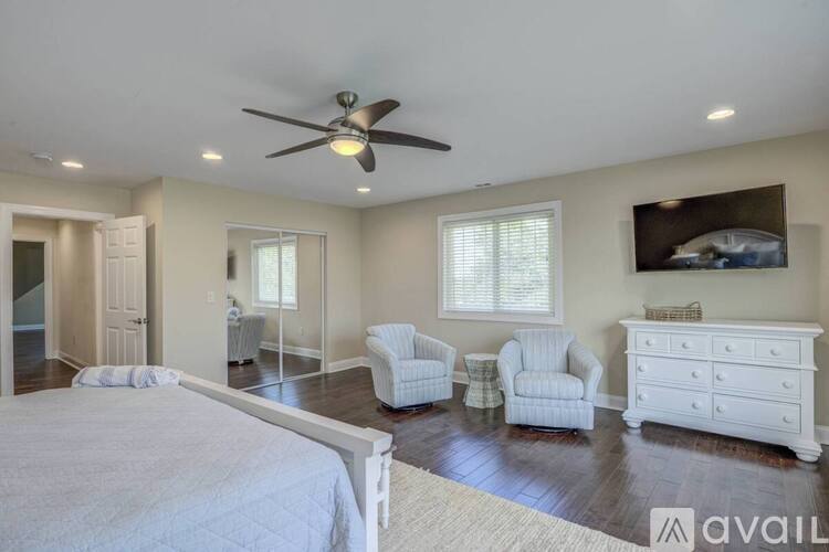 A bedroom with a large bed, a dresser, and a ceiling fan.
