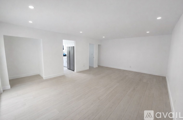 A spacious room with wooden flooring and white walls.