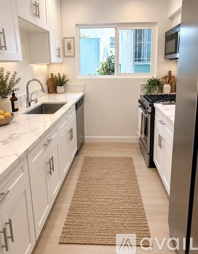 A spacious room with wooden flooring and white walls.