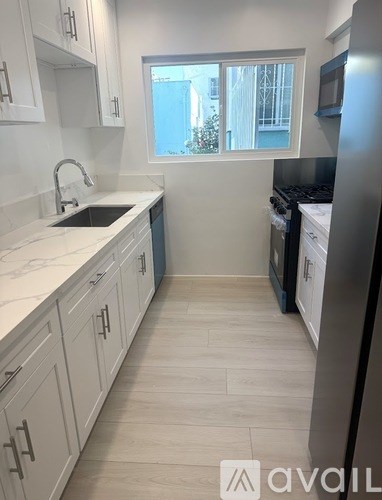 A kitchen with white cabinets and a black refrigerator.