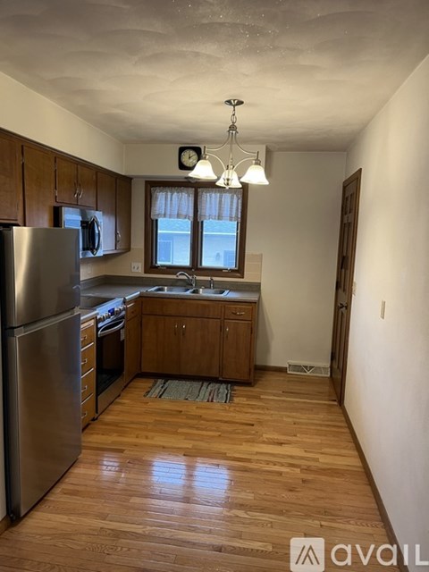 A kitchen with wooden floors and a stainless steel refrigerator.