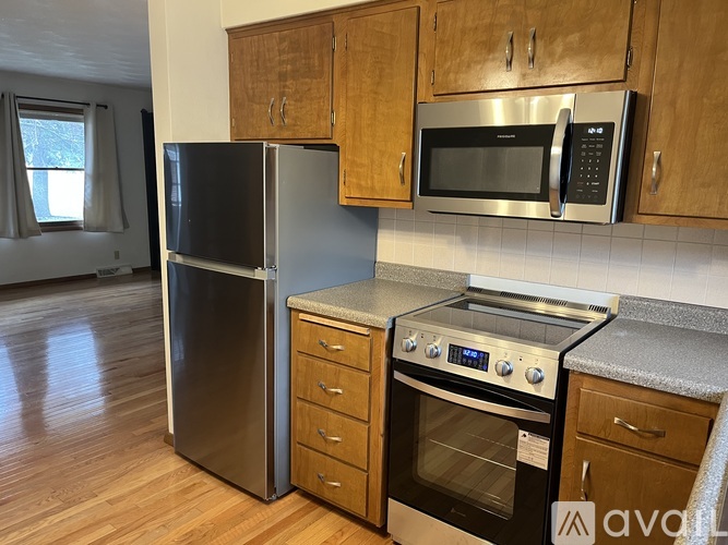 A kitchen with a black fridge, silver oven, and wooden cabinets.