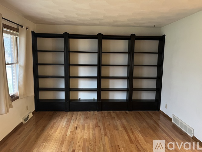 A room with a large black bookshelf and wooden flooring.