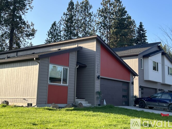 A house with a red door and a grey garage door.