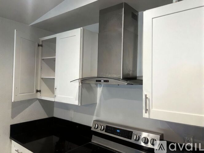 A kitchen with white cabinets and a black countertop.