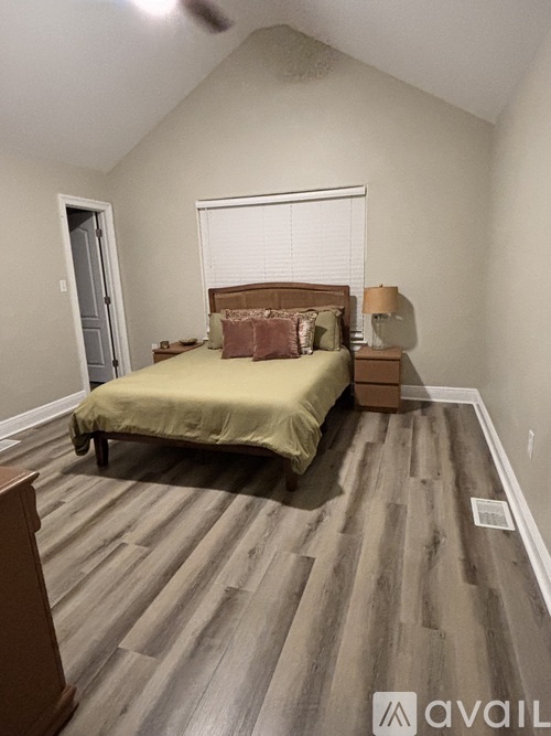 A bedroom with a bed, dresser, and window.