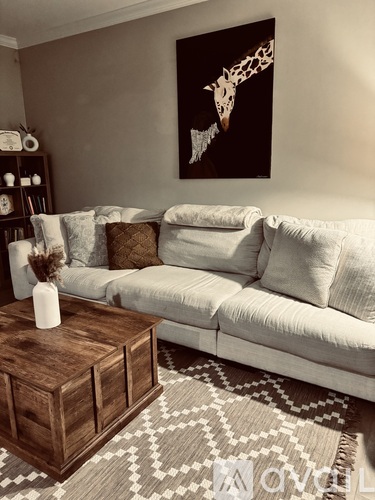 A living room with a white couch, a coffee table, and a giraffe painting on the wall.