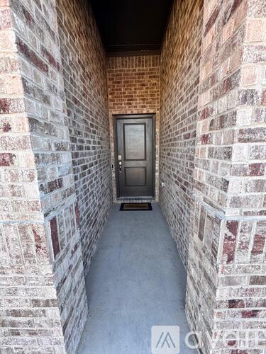 A door is at the end of a brick hallway.