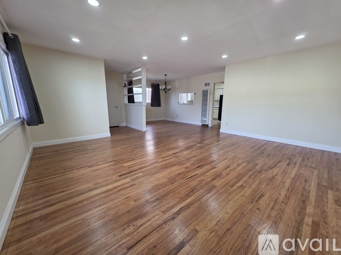 A spacious room with wooden flooring and white walls.
