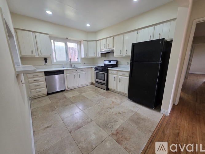 A kitchen with black appliances and white cabinets.