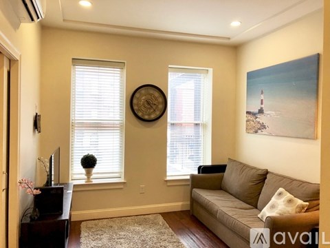 A living room with a couch, television, and a painting of a lighthouse on the wall.