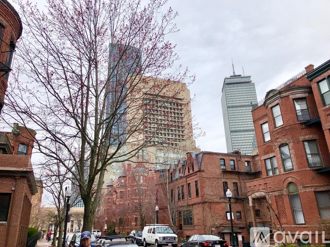 A street view of a city with tall buildings and parked cars.