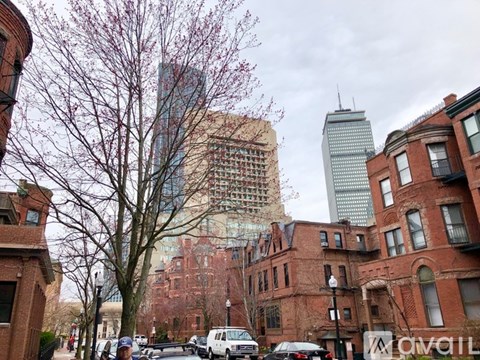 A street view of a city with tall buildings and parked cars.