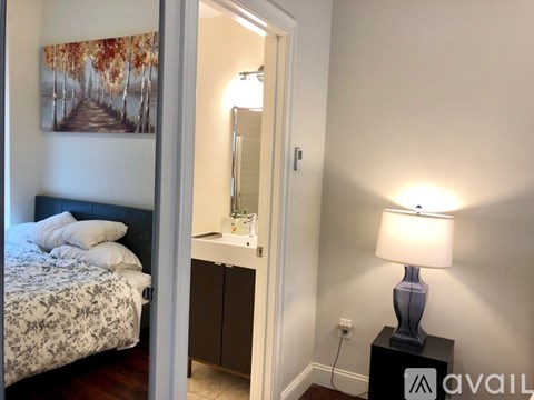 A bedroom with a bed, a nightstand with a lamp, and a painting on the wall.