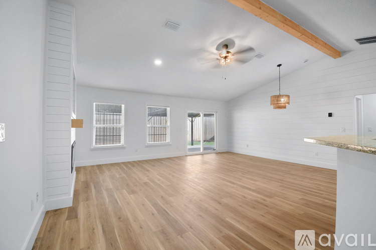 A spacious room with wooden floors and a ceiling fan.