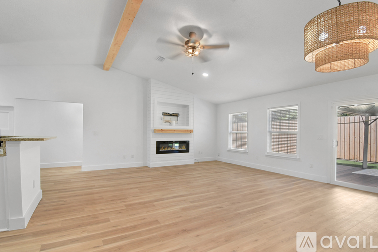 A spacious living room with a fireplace and a ceiling fan.