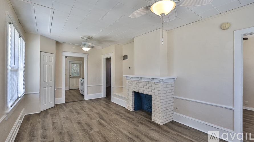 A spacious living room with a fireplace and a fan on the ceiling.