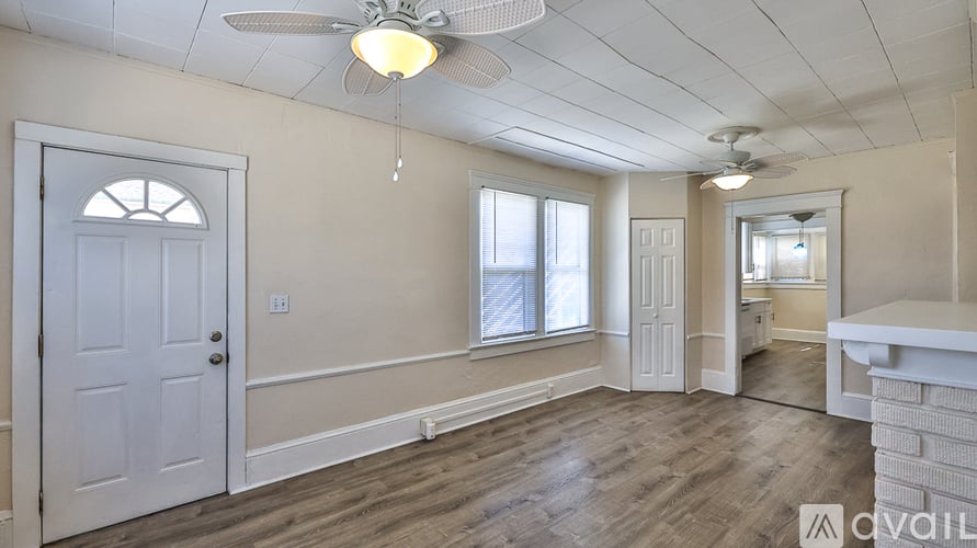 A room with a white door, a window, and a ceiling fan.