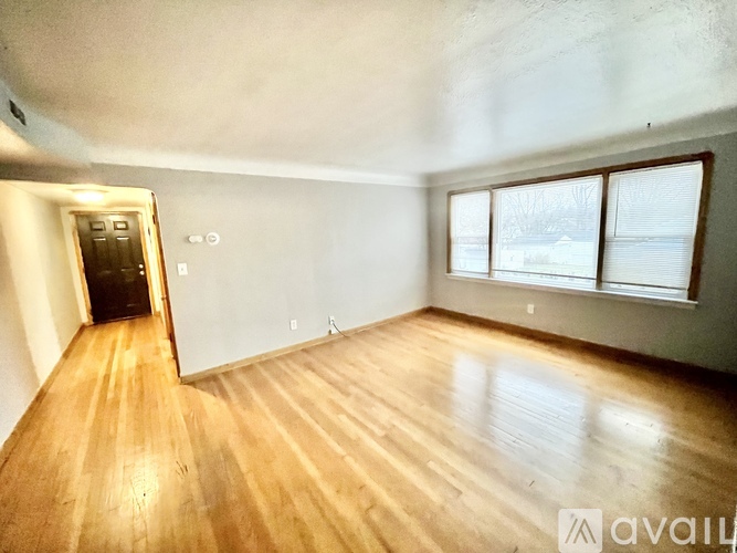 A room with wooden flooring and a door leading to another room.